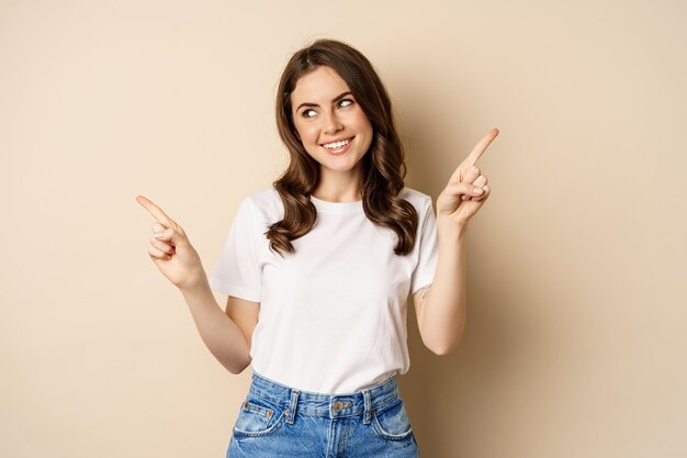 Happy authentic girl smiling pointing fingers sideways showing left and right banner demonstrating p...