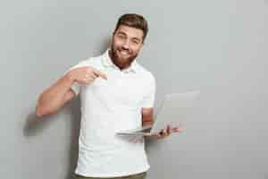 Free photo happy bearded man holding a laptop computer