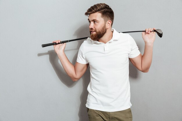 Happy bearded man posing with club and looking away