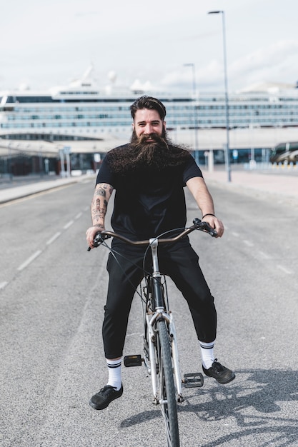 Free photo happy bearded young man riding the bicycle