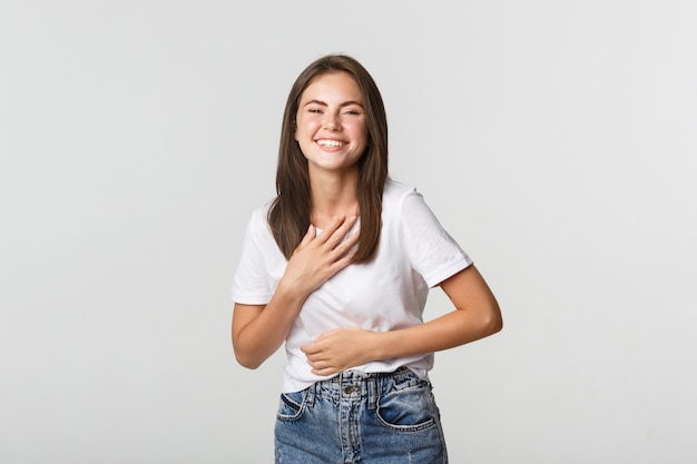 Happy beautiful girl laughing and touching chest, looking thankful