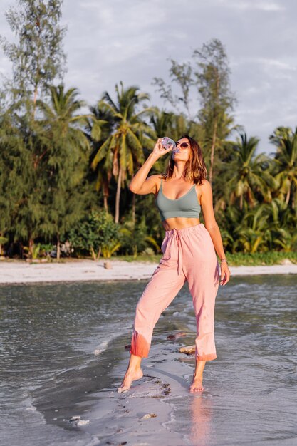 Happy beautiful young european woman with plastic bottle of water in her hand in the beach