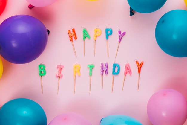 Free Photo happy birthday candles with colorful balloons on pink background