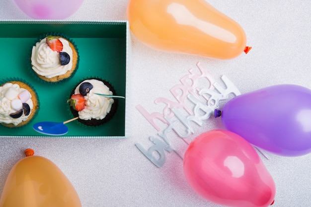 Happy birthday inscription with cupcakes on table