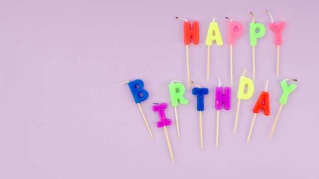 Free photo happy birthday message with colorful candles on purle background