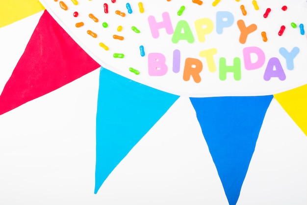 Free photo happy birthday text decorated with candies and bunting on white background