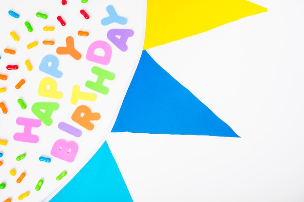 Free Photo happy birthday text with candies and bunting on white backdrop