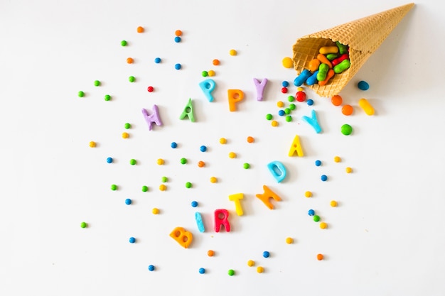 Happy birthday text with candies spilling from waffle ice cream cone