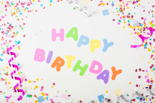 Free photo happy birthday text with confetti and curling streamers on white backdrop