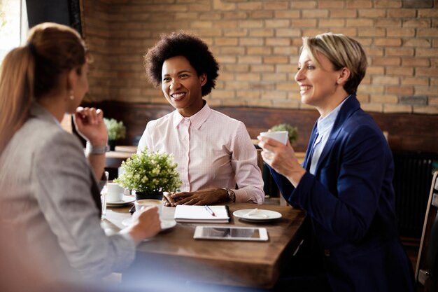 Happy black businesswoman talking to her colleagues in a cafe