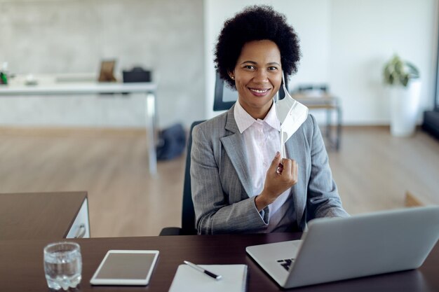 Happy black businesswoman with protective face mask working in the office