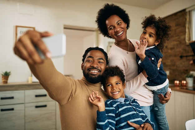 Free photo happy black parents with kids making video call over smart phone at home