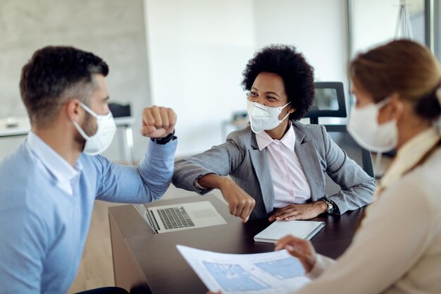 Happy black real estate agent elbow bumping with her client during the meeting