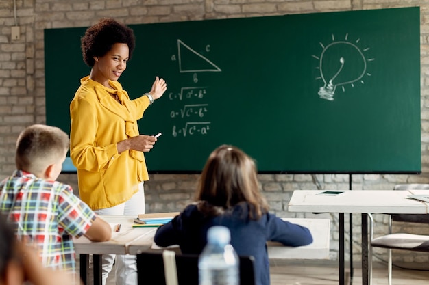 Free photo happy black teacher teaching elementary students math in the classroom