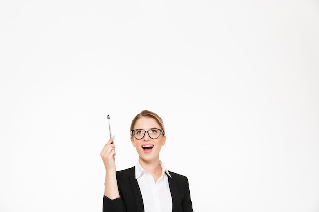 Free Photo happy blonde business woman in eyeglasses pointing and looking up over white wall