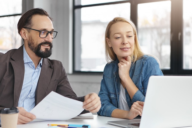 Happy blonde female manager has conversation with male colleague