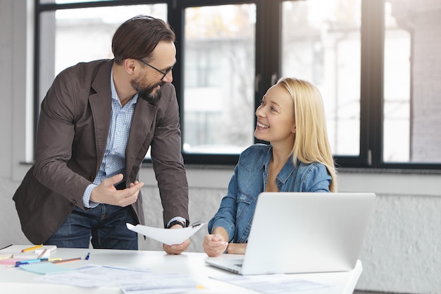 Happy blonde female manager has conversation with male colleague