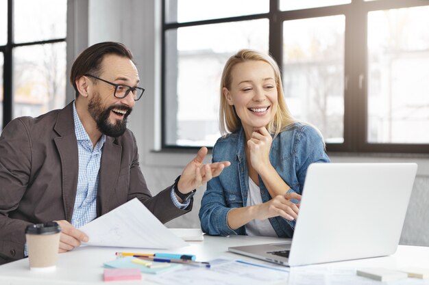 Happy blonde female manager has conversation with male colleague