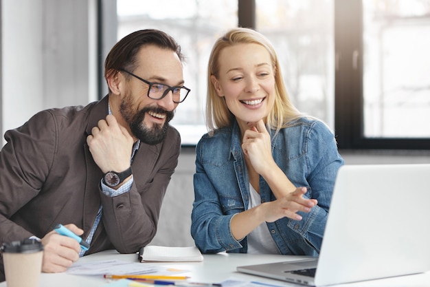 Happy blonde female manager has conversation with male colleague