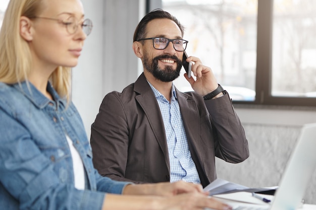 Happy blonde female manager has conversation with male colleague