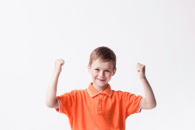 Happy boy clenching fist making yes gesture on white wall