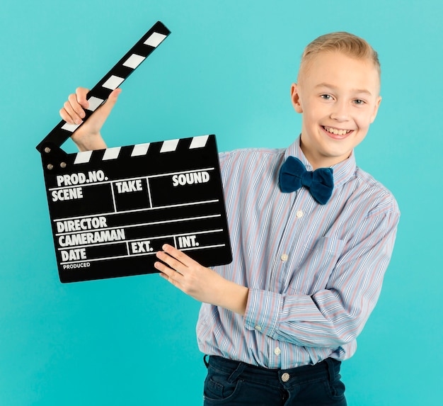 Free photo happy boy holding clapperboard front view