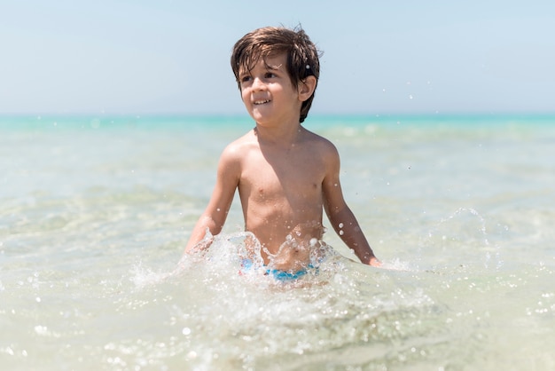 Free photo happy boy playing in water at the seaside