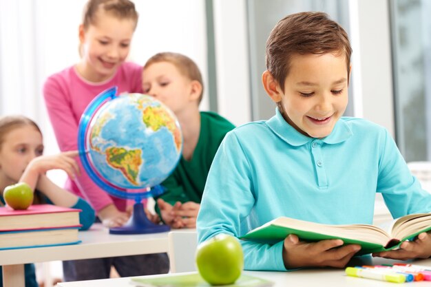 Happy boy reading a book close to an apple