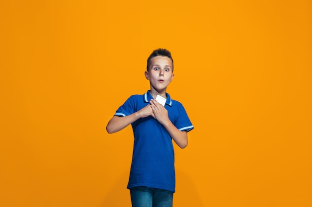 Free Photo the happy boy standing and smiling against orange wall