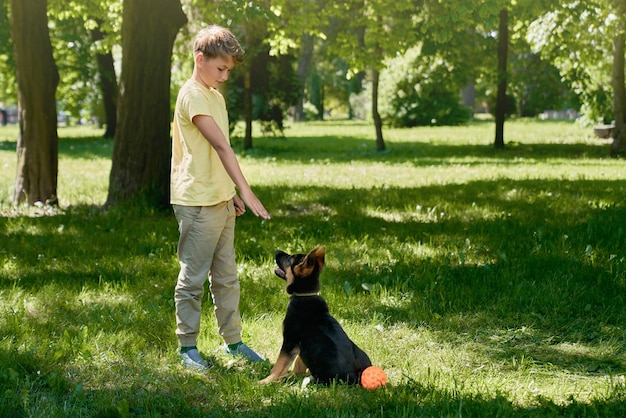 Happy boy training little puppy at city park