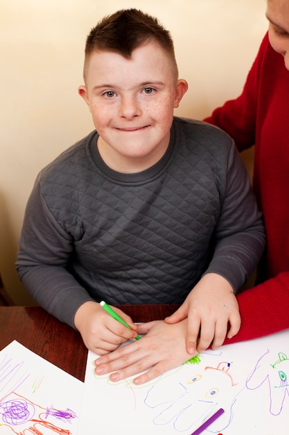 Free Photo happy boy with down syndrome drawing