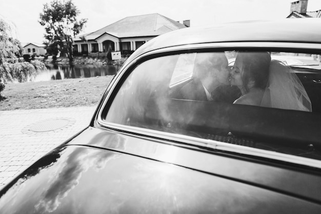 Happy brides are kissing in the car