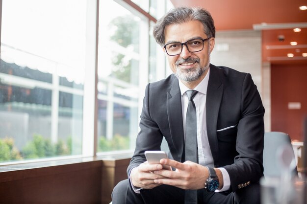 Happy Business Leader Using Smartphone in Lobby