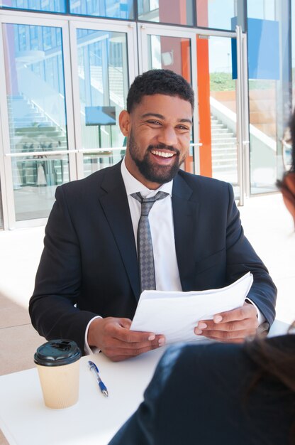 Happy business man discussing documents with partner in cafe