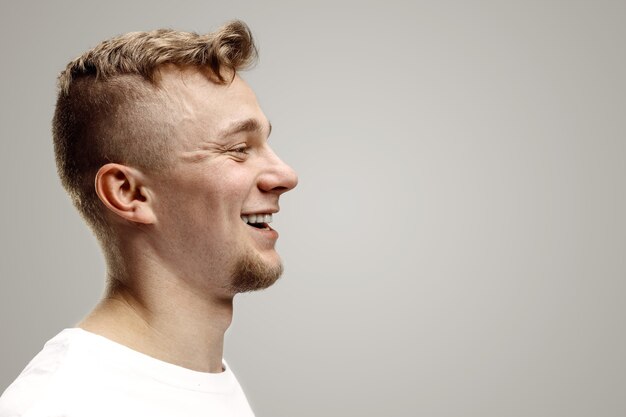 Happy business man standing, smiling isolated on gray studio background. Beautiful male profile portrait. Young satisfy man. Human emotions, facial expression concept.