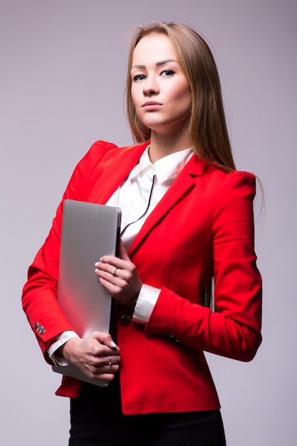 Happy business woman holding laptop computer over gray wall