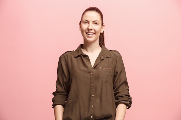 Happy business woman standing and smiling against pink wall.