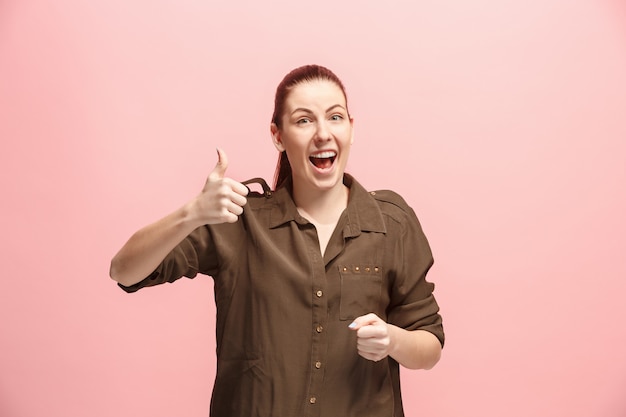 The happy business woman standing and smiling against pink wall.