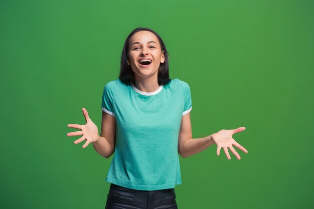 Happy business woman standing and smiling isolated on green studio background. Beautiful female half-length portrait. Young emotional woman. The human emotions, facial expression concept. Front view.