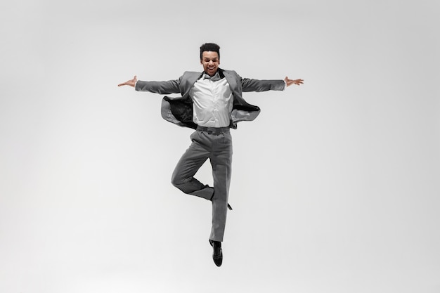 Free photo happy businessman dancing in motion isolated on white studio background. flexibility and grace in business. human emotions concept. office, success, professional, happiness, expression concepts