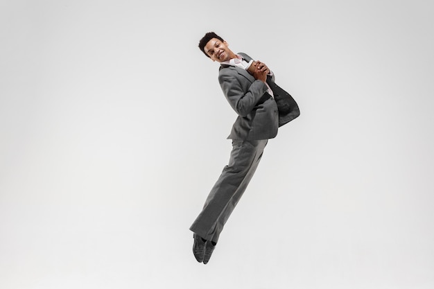 Free photo happy businessman dancing in motion isolated on white studio background. flexibility and grace in business. human emotions concept. office, success, professional, happiness, expression concepts