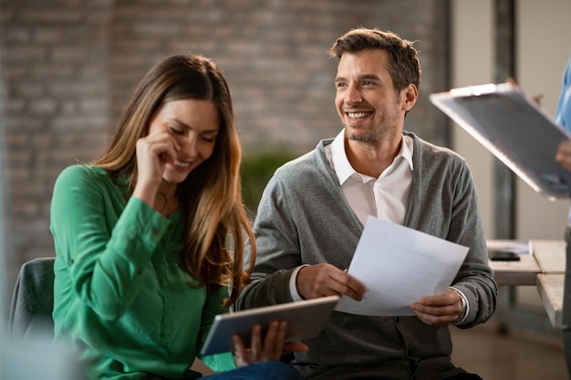 Happy businessman and his female colleague laughing while being on a meeting in bard room