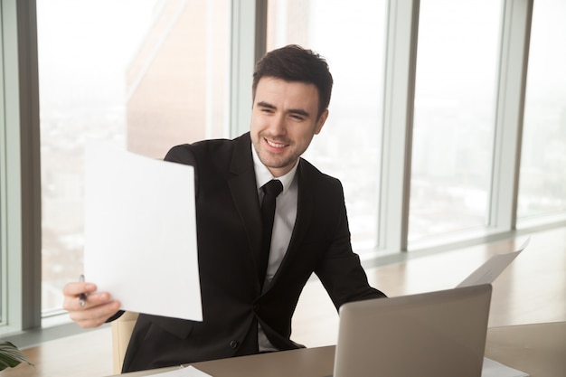 Happy businessman holding financial statistics report, satisfied