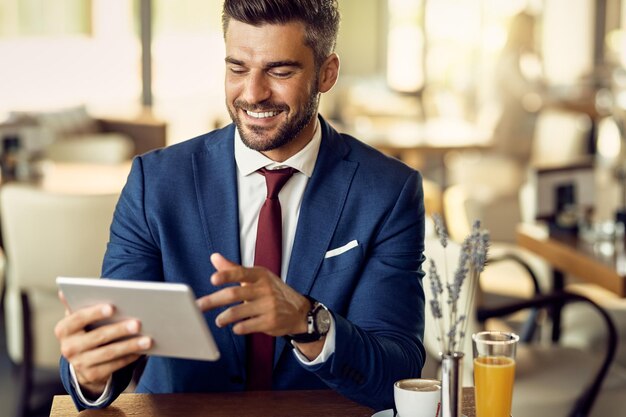 Happy businessman using digital tablet in a cafe