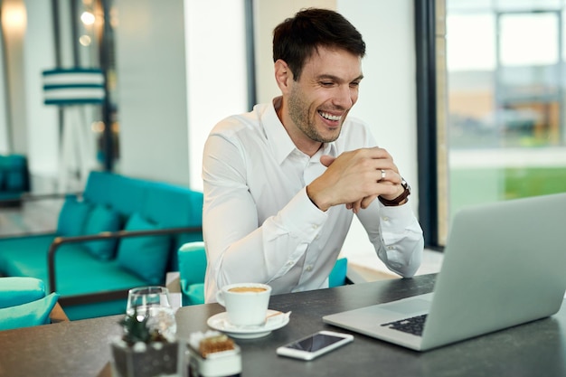 Free Photo happy businessman using laptop while having coffee break in a cafe