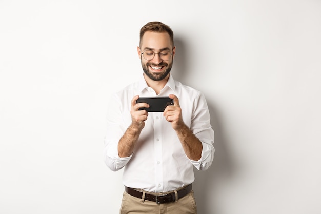 Happy businessman watching video on mobile phone, standing  .