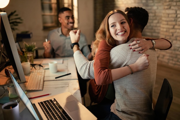 Happy businesswoman embracing her coworker while celebrating success in the office