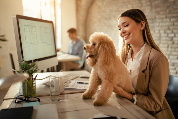 Free photo happy businesswoman enjoying with her dog while working in the office