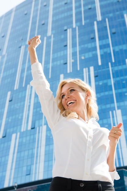 Free Photo happy businesswoman is the winner. beautiful lady in white blouse raised her hand and smiling because of success.