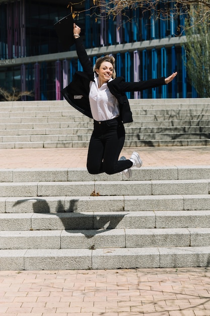 Free photo happy businesswoman jumping in front of stairs